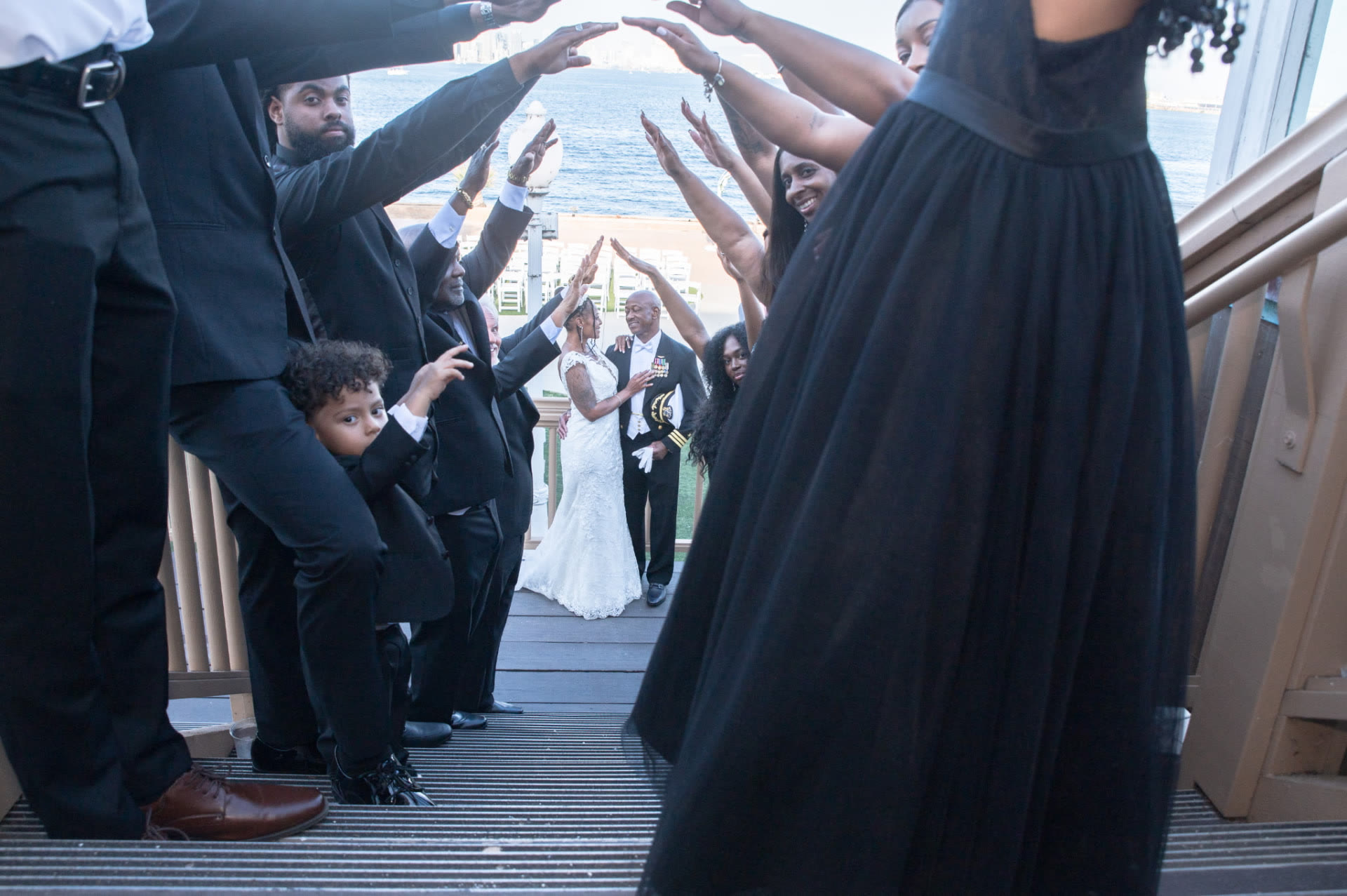 Wedding party lining a staircase arch for the couple's first look by the bay
