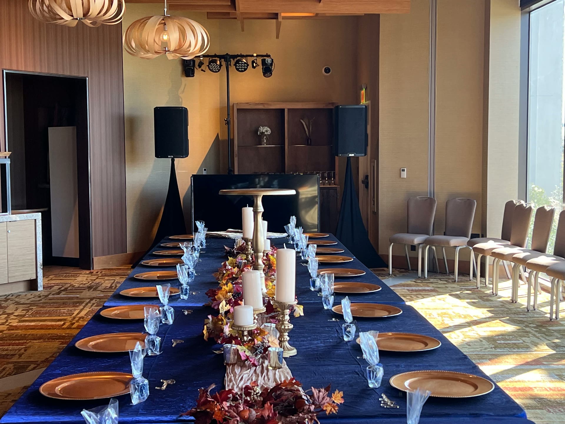 Head table setup with gold chargers and truss-mounted lighting in a conference hall