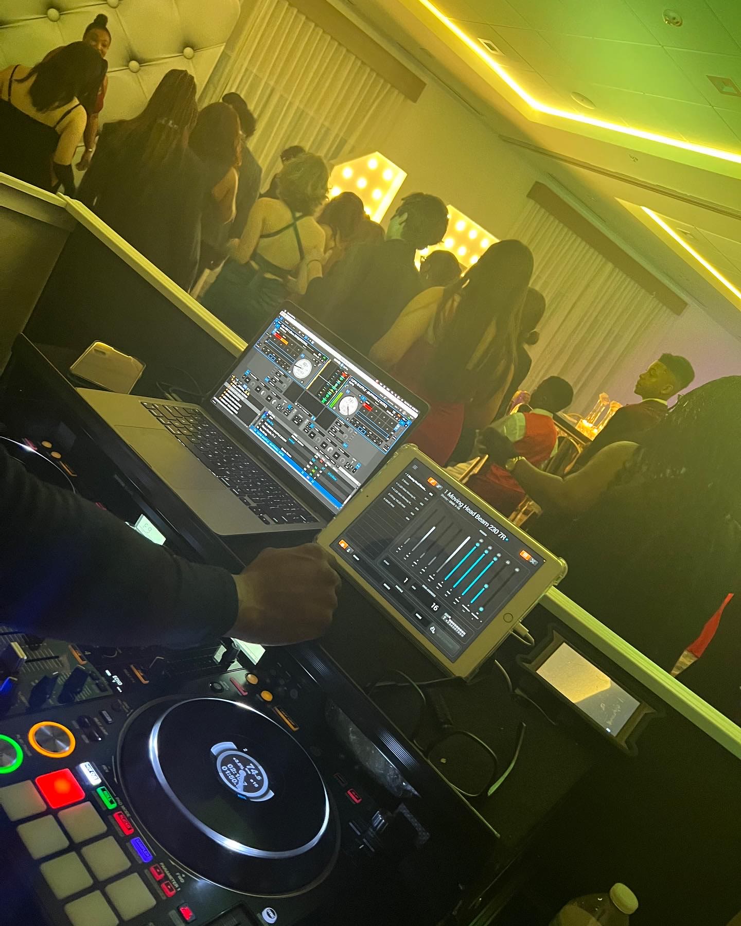 DJ mixing on a Pioneer controller while guests dance under warm uplighting