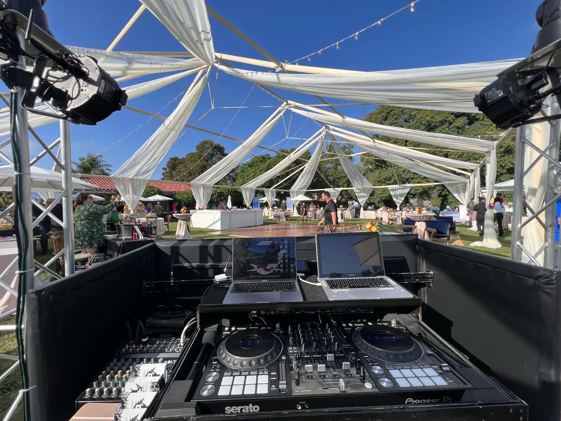 Elegant tented outdoor wedding with draped ceiling and Serato DJ setup