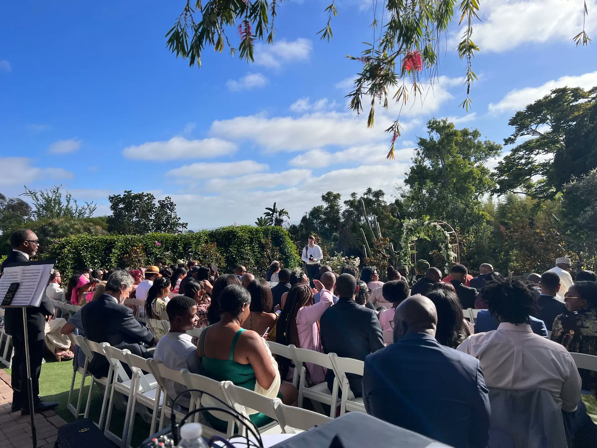 Outdoor garden wedding ceremony with white chairs and clear blue sky