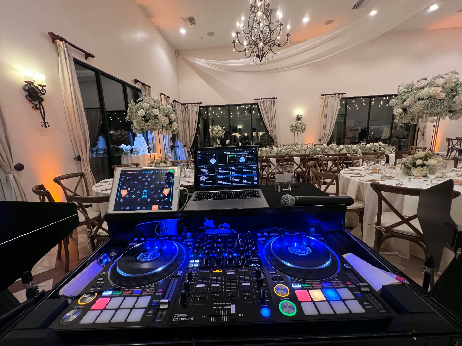 Elegant estate wedding reception with a blue-lit DJ controller and rose centerpieces