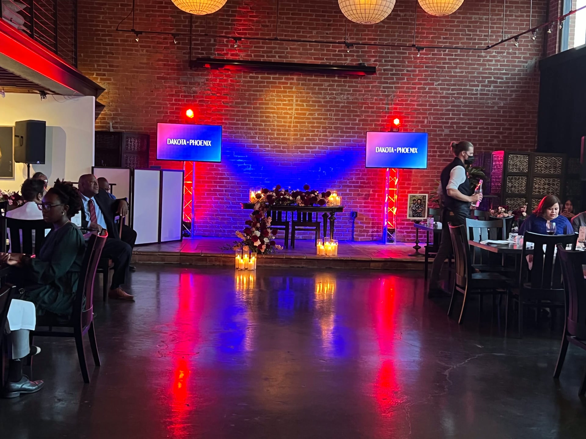 Wedding reception stage with red and blue uplighting and custom monogram screens
