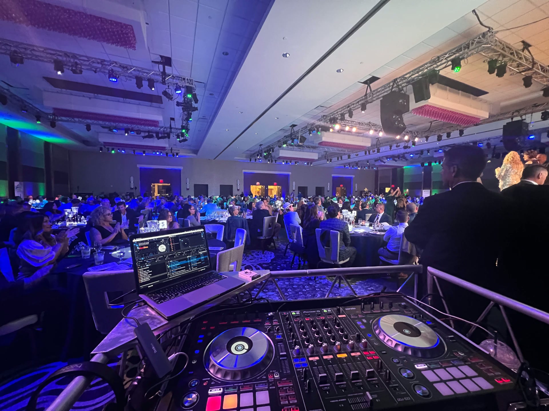 Large corporate gala ballroom with truss lighting and packed tables